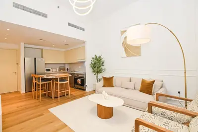 a living room with a couch and a table at GV Holiday Homes DXB - Cozy 2BR Apartment in Town Square Dubai in Dubai