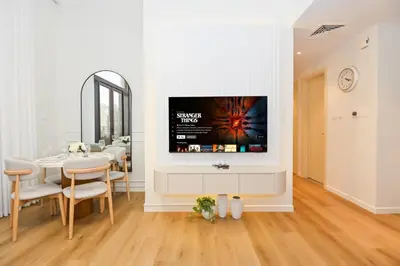 a living room with a tv on a wall at GV Holiday Homes DXB - Cozy 2BR Apartment in Town Square Dubai in Dubai