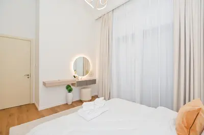 a white bedroom with a bed and a mirror at GV Holiday Homes DXB - Cozy 2BR Apartment in Town Square Dubai in Dubai