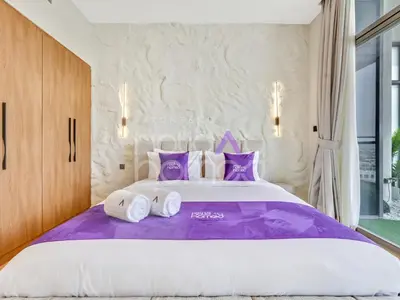 a bedroom with a large bed with purple pillows at Modern 2BR Gem Full Golf Views & Pool in Dubai