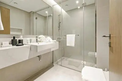 a white bathroom with a sink and a shower at 2BR plus Maid CF7 B Stylish Stay with Large Balcony in Dubai
