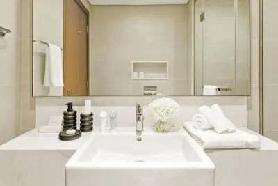a white bathroom with a sink and a mirror at 2BR plus Maid CF7 B Stylish Stay with Large Balcony in Dubai