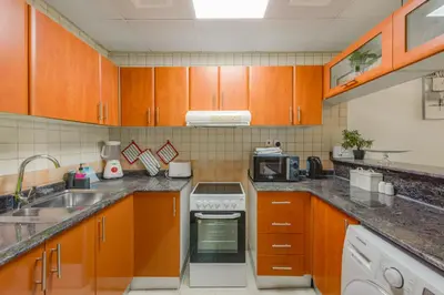 a kitchen with wooden cabinets and a stove top oven at Spacious 1BR in Great Location, Manchester Tower, Dubai Marina in Dubai