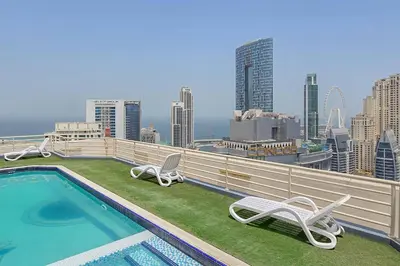 a balcony with a swimming pool and chairs and a city skyline at Spacious 1BR in Great Location, Manchester Tower, Dubai Marina in Dubai