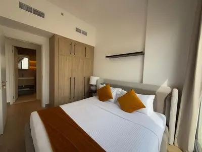 a bedroom with a large white bed with orange pillows at 1 Bedroom Apartment in Liva by the S Holiday Homes in Dubai