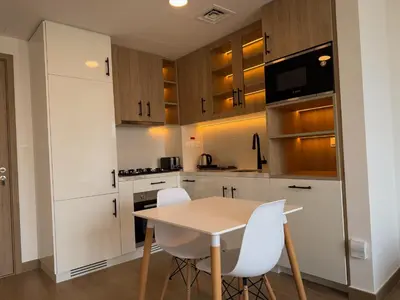 a kitchen with white cabinets and a table and chairs at 1 Bedroom Apartment in Liva by the S Holiday Homes in Dubai
