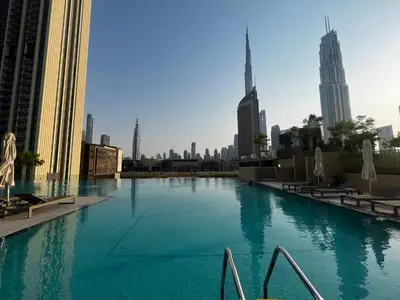 a large swimming pool in a city with tall buildings at 2min Walk to Dubai Mall - 2BR - Infinity Pool & Gym - Burj Khalifa in Dubai