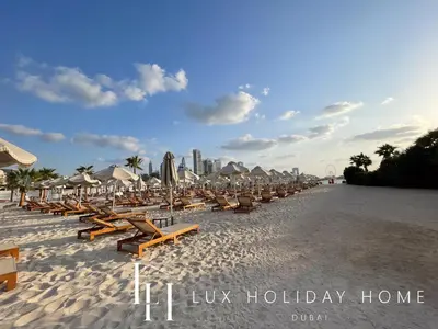a row of beach chairs and umbrellas on a beach at LUX The Seven Res Palm Studio in Dubai
