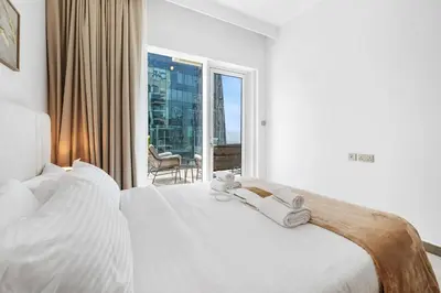 a bedroom with a bed with white sheets and a window at BLVD - Missoni Canal View - Walk to Dubai Mall in Dubai