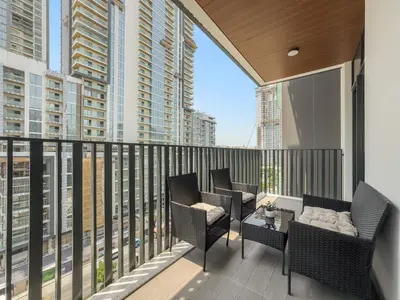 a balcony with chairs and a table with a view of buildings at 1BR Luxury Stay in Sobha Hartland in Dubai