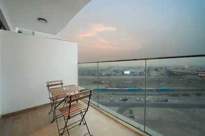 a balcony with two chairs and a view of an airport at EasyGo- Comfy, near metro, Easy Access to City Roads in Dubai