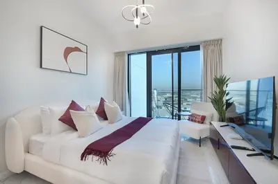a white bedroom with a large bed and a balcony at EasyGo- Comfy, near metro, Easy Access to City Roads in Dubai