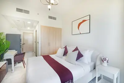 a white bedroom with a bed and a desk at EasyGo- Comfy, near metro, Easy Access to City Roads in Dubai
