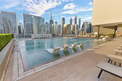 a large swimming pool with chairs and a city skyline at Waves - Stylish Studio Near Downtown Dubai in Dubai
