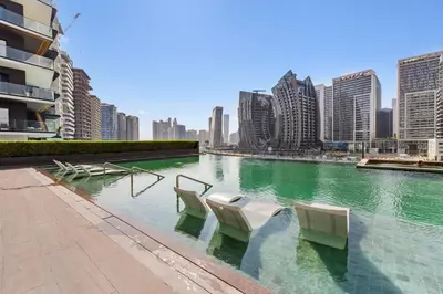 a pool with chairs and buildings in a city at Waves - Stylish Studio Near Downtown Dubai in Dubai
