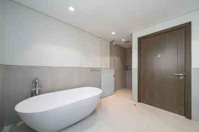 a bathroom with a white tub and a wooden door at Prestige Jumeirah 4BR Villa with Rooftop and Private Garden in Dubai