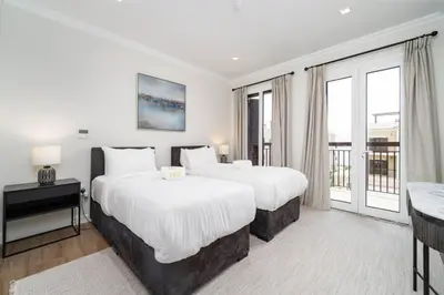 two beds in a hotel room with a balcony at Prestige Jumeirah 4BR Villa with Rooftop and Private Garden in Dubai