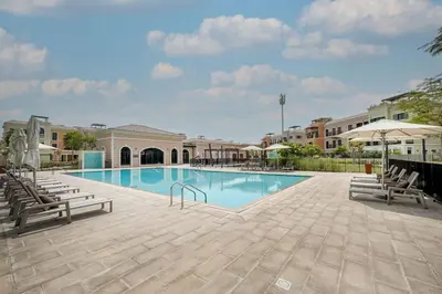 a large swimming pool with chairs and umbrellas at Prestige Jumeirah 4BR Villa with Rooftop and Private Garden in Dubai