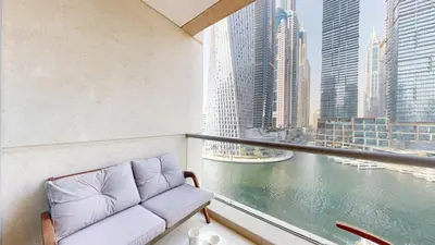 a couch on a balcony with a view of the water at Iris Blue - Colourful One Bedroom in The Marina in Dubai