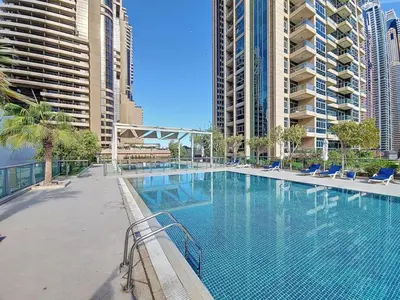 a large swimming pool with blue chairs and buildings at Iris Blue - Colourful One Bedroom in The Marina in Dubai