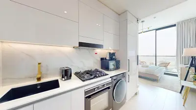 a white kitchen with a stove and a sink at Binghatti Tulip - High Rise Upgraded Studio in JVC in Dubai