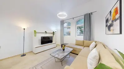 a living room with a couch and a tv at Sherlock House 2 - Peaceful One Bed in Motor City in Dubai
