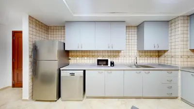 a kitchen with white cabinets and a stainless steel refrigerator at Sherlock House 2 - Peaceful One Bed in Motor City in Dubai