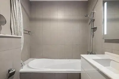 a white bathroom with a tub and a sink at Palm Jumeirah Luxury Apt Direct Beach Access & Views in Dubai