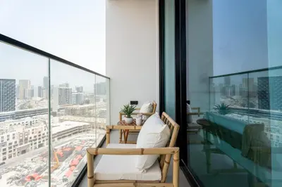 a person sitting in a chair on a balcony looking out at the city at GuestReady - Top-Floor Tranquillity in JVC in Dubai