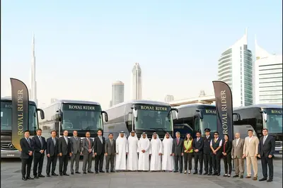 a group of men in suits standing in front of buses at Royal Rider Bus rental Dubai in Dubai