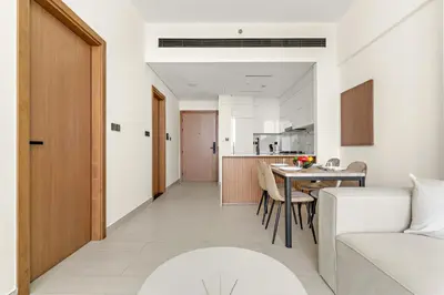 a living room and kitchen with a table and a couch at Vayk - Modern 1BR Apartment in JVC in Dubai