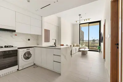 a kitchen with white cabinets and a dishwasher at Vayk - Modern 1BR Apartment in JVC in Dubai