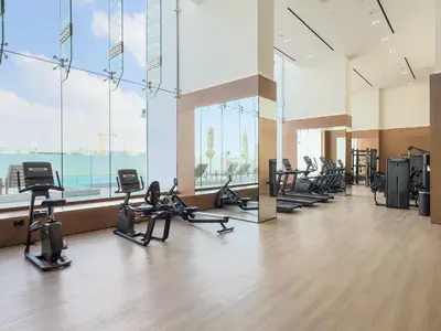 a gym with a row of treadmills and ellipticals at Vayk - Modern 1BR Apartment in JVC in Dubai