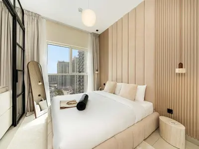 a bedroom with a large white bed and a window at Modern 1BR with Cinema, Pool and Gym Dubai Hills in Dubai