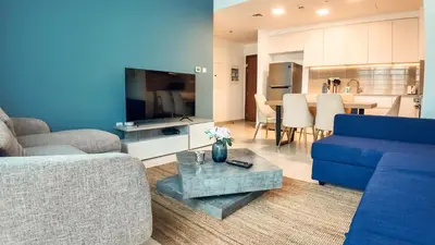 a living room with a blue couch and a table at Silk Valley - Modern 2BR Near Park & Attractions in Dubai