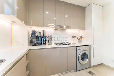 a white kitchen with a washing machine in it at Peaceful 1BR with Community View, Quick Downtown and Golf Club Access, Azizi Riviera 34, Al Merkadh by Deluxe Holiday Homes in Dubai