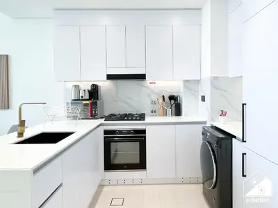 a white kitchen with white cabinets and a dishwasher at Stylish 1BR Retreat in Binghatti Amber l Balcony in Dubai