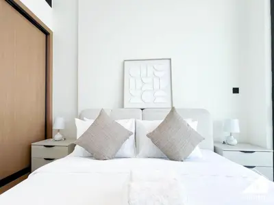 a white bedroom with a large white bed with pillows at Stylish 1BR Retreat in Binghatti Amber l Balcony in Dubai
