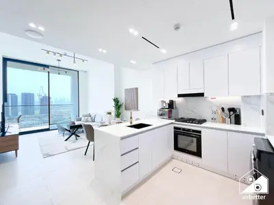 a kitchen with white cabinets and a dining room at Chic Binghatti Amber 1BR l Balcony & Comfort in Dubai