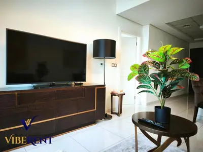 a living room with a flat screen tv and a plant at Damac 1BHK, Terrance Pool, 20 Min to Downtown in Dubai