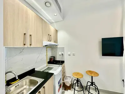 a kitchen with a sink and two stools in it at Stunning studio with balcony close to metro in Dubai