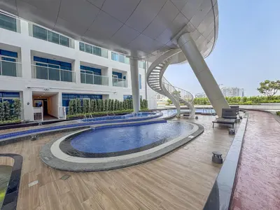 a building with a swimming pool and a spiral staircase at Vogue Arjan Opalz by Danube near Science Park, Studio Apartment with Balcony and Vibrant Community View, Access to all Amenities in Dubai