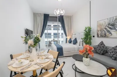 a living room with a couch and a table with chairs at Vogue Arjan Opalz by Danube near Science Park, Studio Apartment with Balcony and Vibrant Community View, Access to all Amenities in Dubai