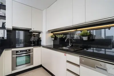 a kitchen with white cabinets and black counter tops at Waterfront Luxury 2 Bed in Marina Mall Hotel in Dubai