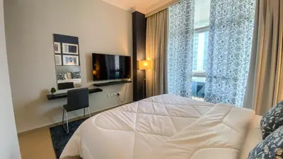 a bedroom with a white bed and a television at Sea Breeze Luxury 2BR, Dubai Marina, Big Terrace, Near Beach, Pool access, by Stay Vista! for up to 6 Guests in Dubai