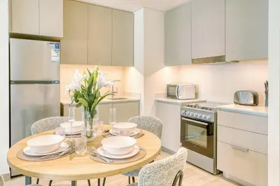 a kitchen and dining room with a wooden table and chairs at PVH - Charming 1 BR - Lotus Creek Beach in Dubai