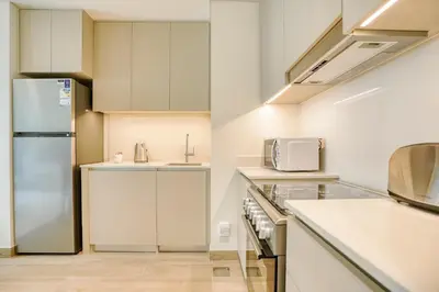 a kitchen with white cabinets and a refrigerator at PVH - Charming 1 BR - Lotus Creek Beach in Dubai