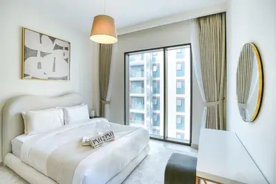 a white bedroom with a bed and a large window at PVH - Charming 1 BR - Lotus Creek Beach in Dubai