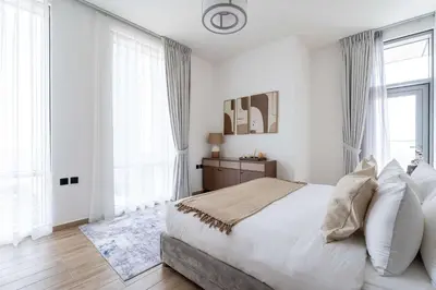 a white bedroom with a large bed and large windows at Luxury 2BR with Canal & Pool View Nr Downtown in Dubai
