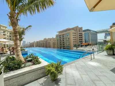 a large swimming pool with palm trees and buildings at Steps from Nakheel Mall and Monorail Station, Near Beach Clubs ,15 Mins to Downtown and Marina, The Palm Tower, Palm Jumeirah by Deluxe Holiday Homes in Dubai